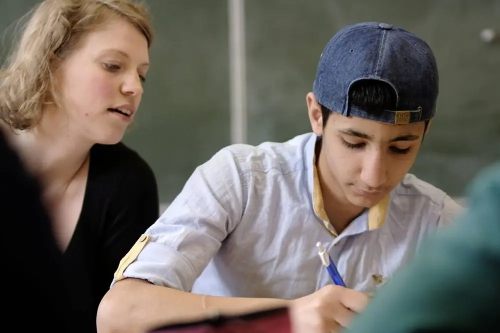 A college graduate helps a student with his assignments.